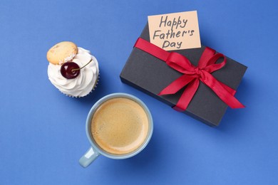 Photo of Card with phrase Happy Father's Day, gift box, cupcake and cup with coffee on blue background, flat lay