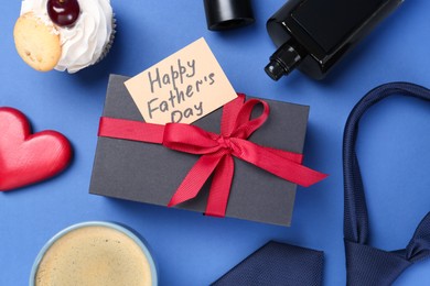 Photo of Card with phrase Happy Father's Day, gift box, cupcake, perfume and cup with coffee on blue background, flat lay