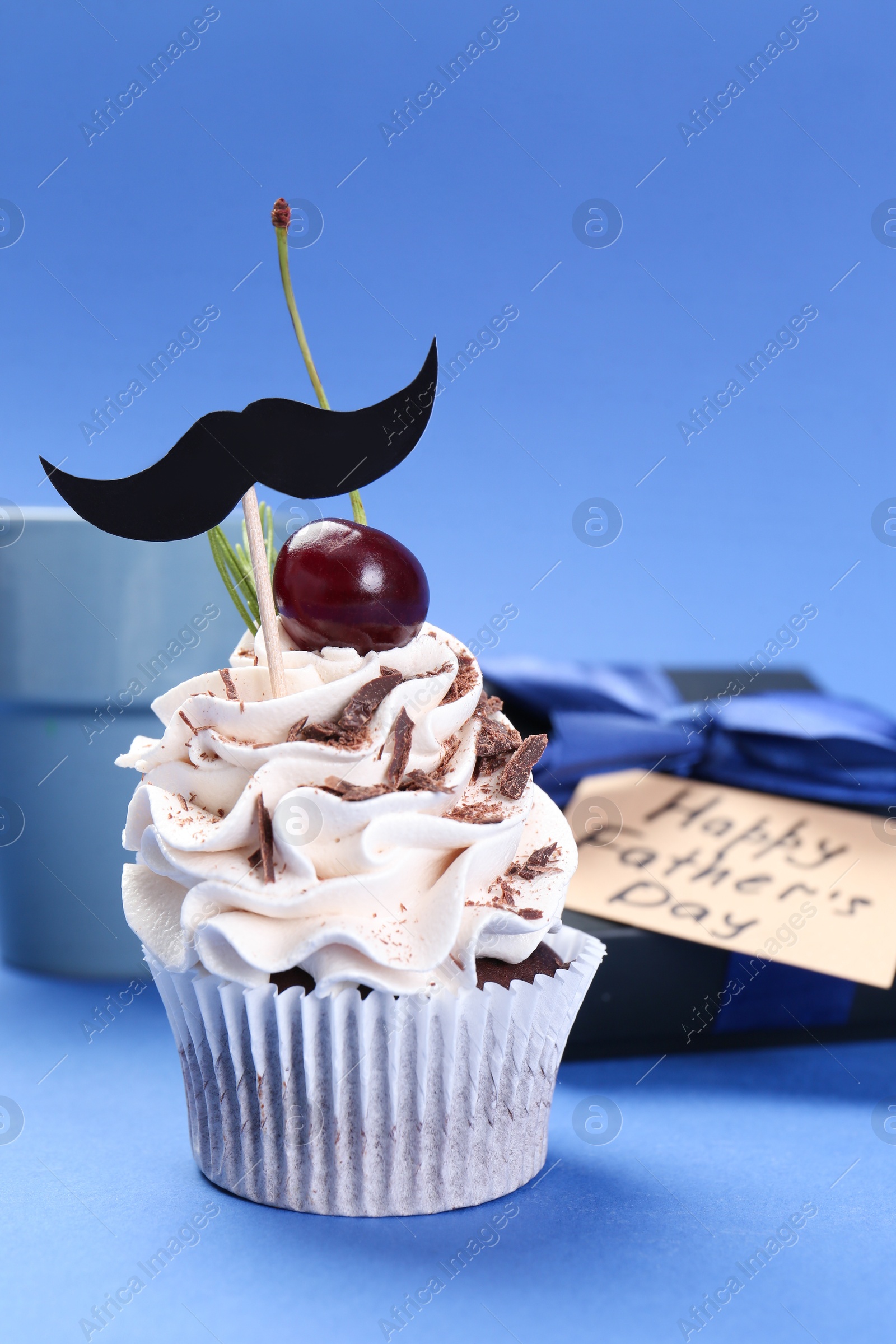 Photo of Happy Father's Day. Cupcake with mustache topper on blue background, closeup