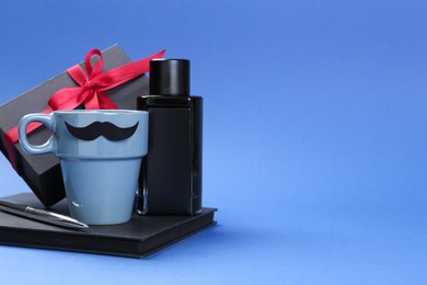 Photo of Happy Father's Day. Cup of coffee, notebook, pen, perfume and gift box on blue background. Space for text