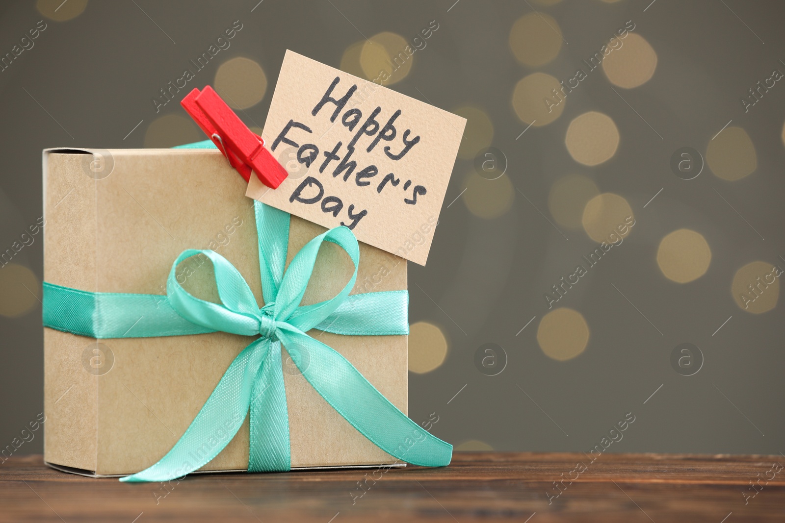 Photo of Greeting card with phrase Happy Father's Day and gift box on wooden table, space for text