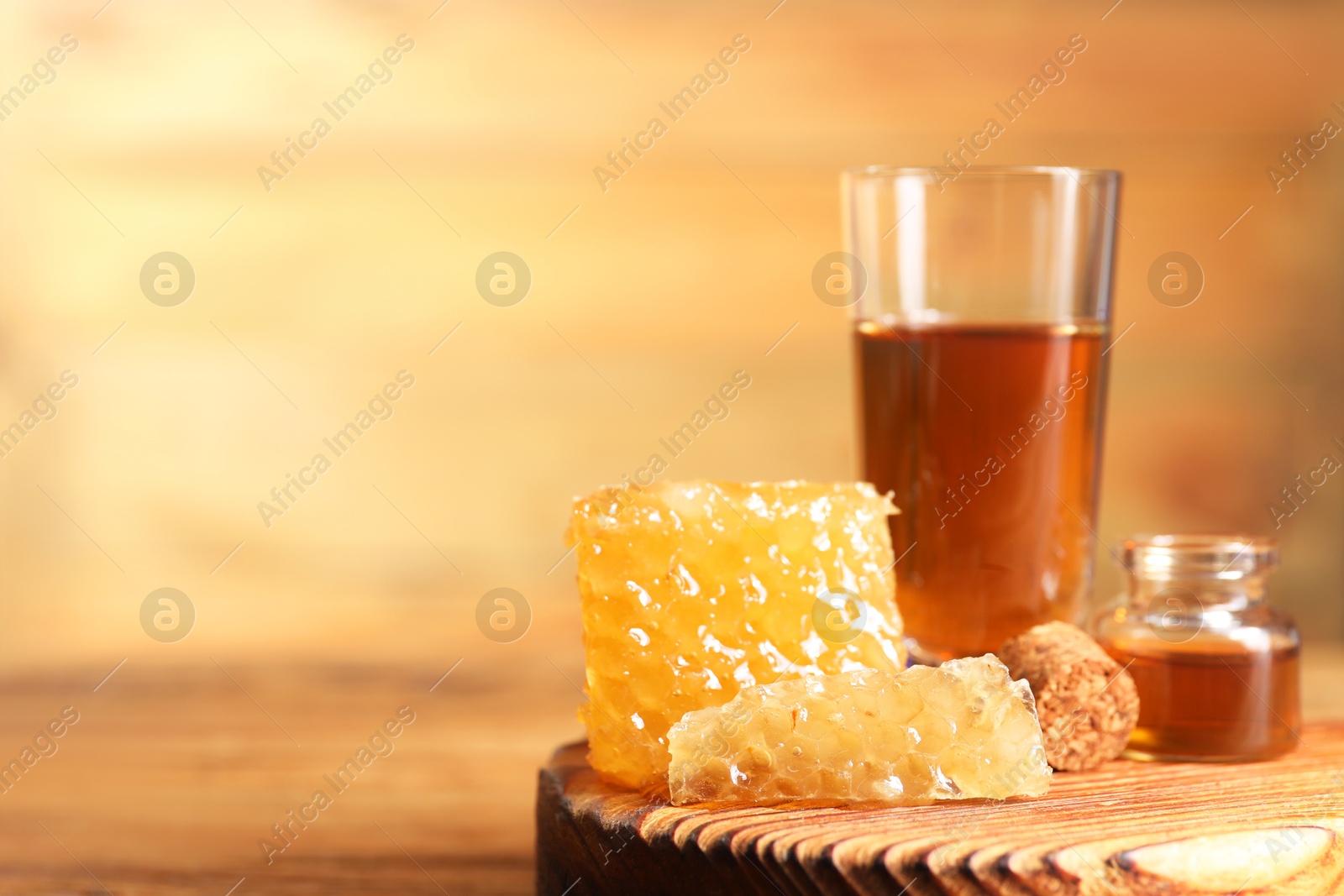 Photo of Natural honey tincture and sweet honeycombs on wooden table, closeup. Space for text