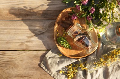 Tincture and different ingredients on wooden table, top view. Space for text