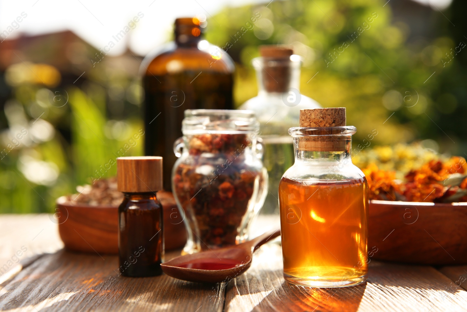 Photo of Different tinctures and ingredients on wooden table outdoors