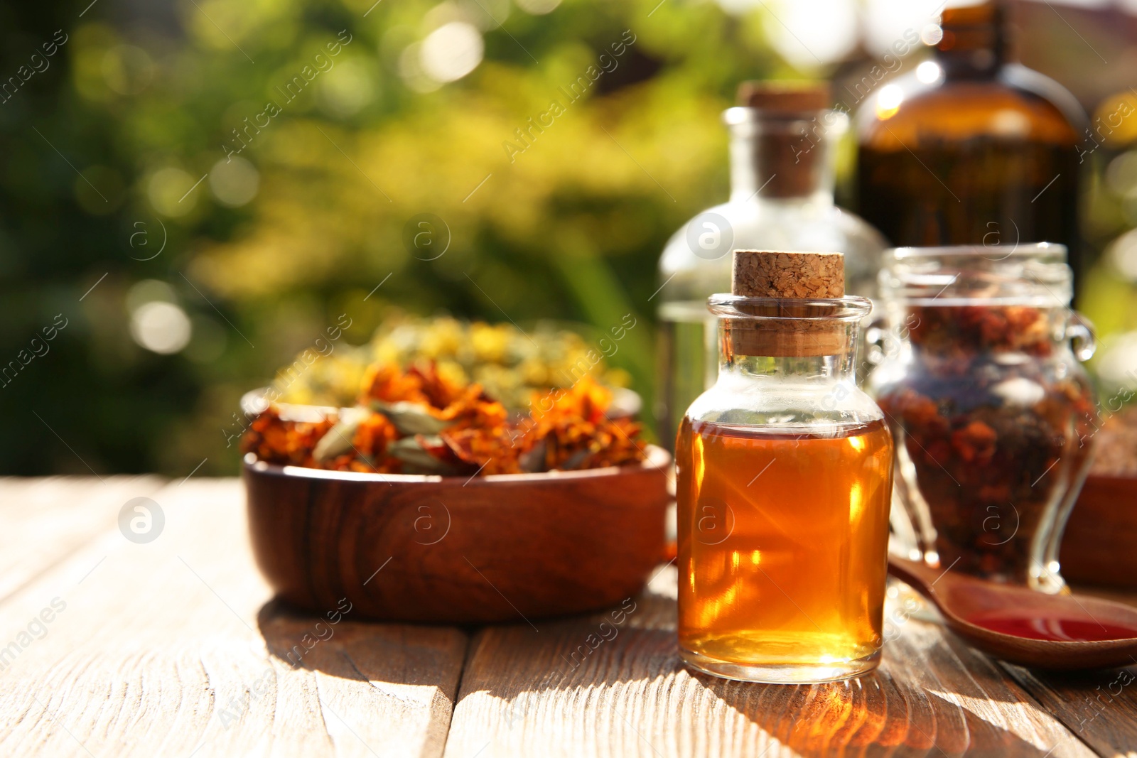 Photo of Different tinctures and ingredients on wooden table outdoors