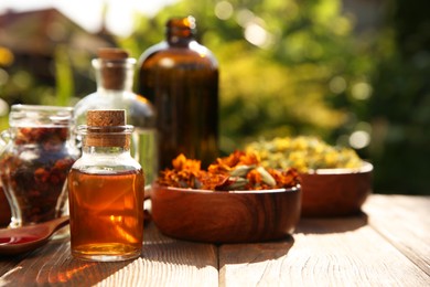 Photo of Different tinctures and ingredients on wooden table outdoors