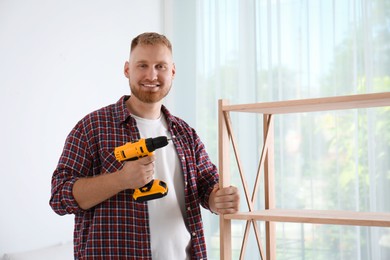 Photo of Man with electric screwdriver at home. Assembling furniture