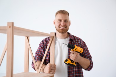 Photo of Man with electric screwdriver at home. Assembling furniture