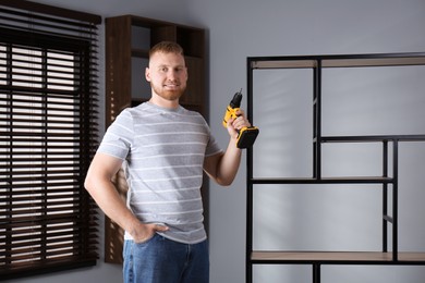 Photo of Man with electric screwdriver at home. Assembling furniture