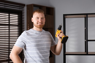 Photo of Man with electric screwdriver at home. Assembling furniture