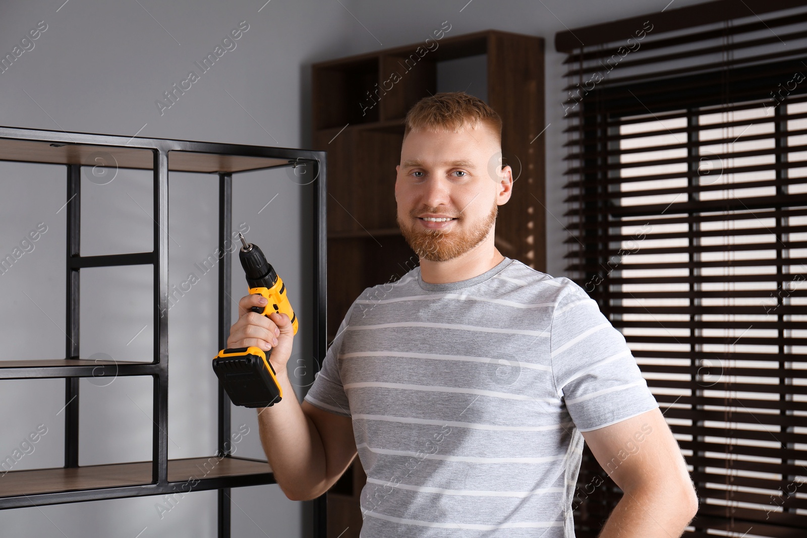 Photo of Man with electric screwdriver at home. Assembling furniture