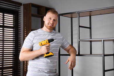 Photo of Man with electric screwdriver at home. Assembling furniture