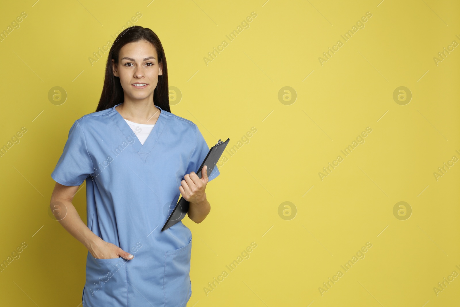 Photo of Portrait of smiling nurse with clipboard on yellow background. Space for text