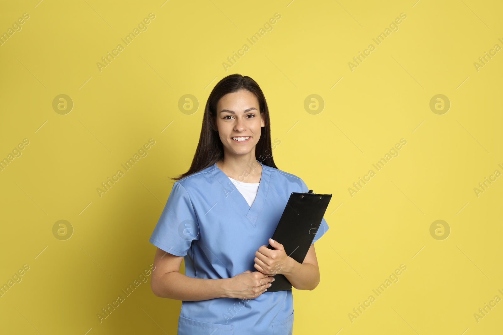 Photo of Portrait of smiling nurse with clipboard on yellow background