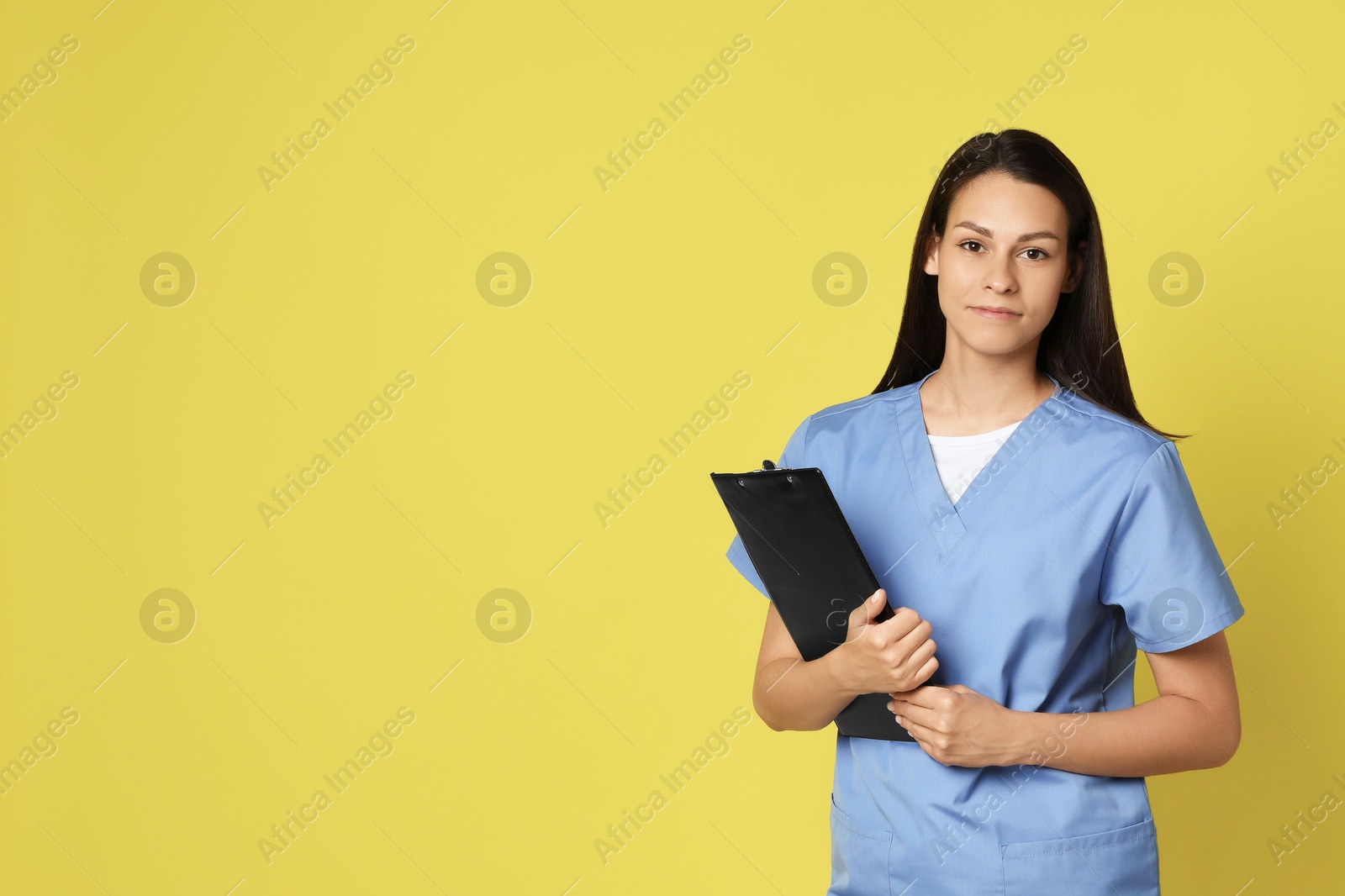 Photo of Portrait of beautiful nurse with clipboard on yellow background. Space for text