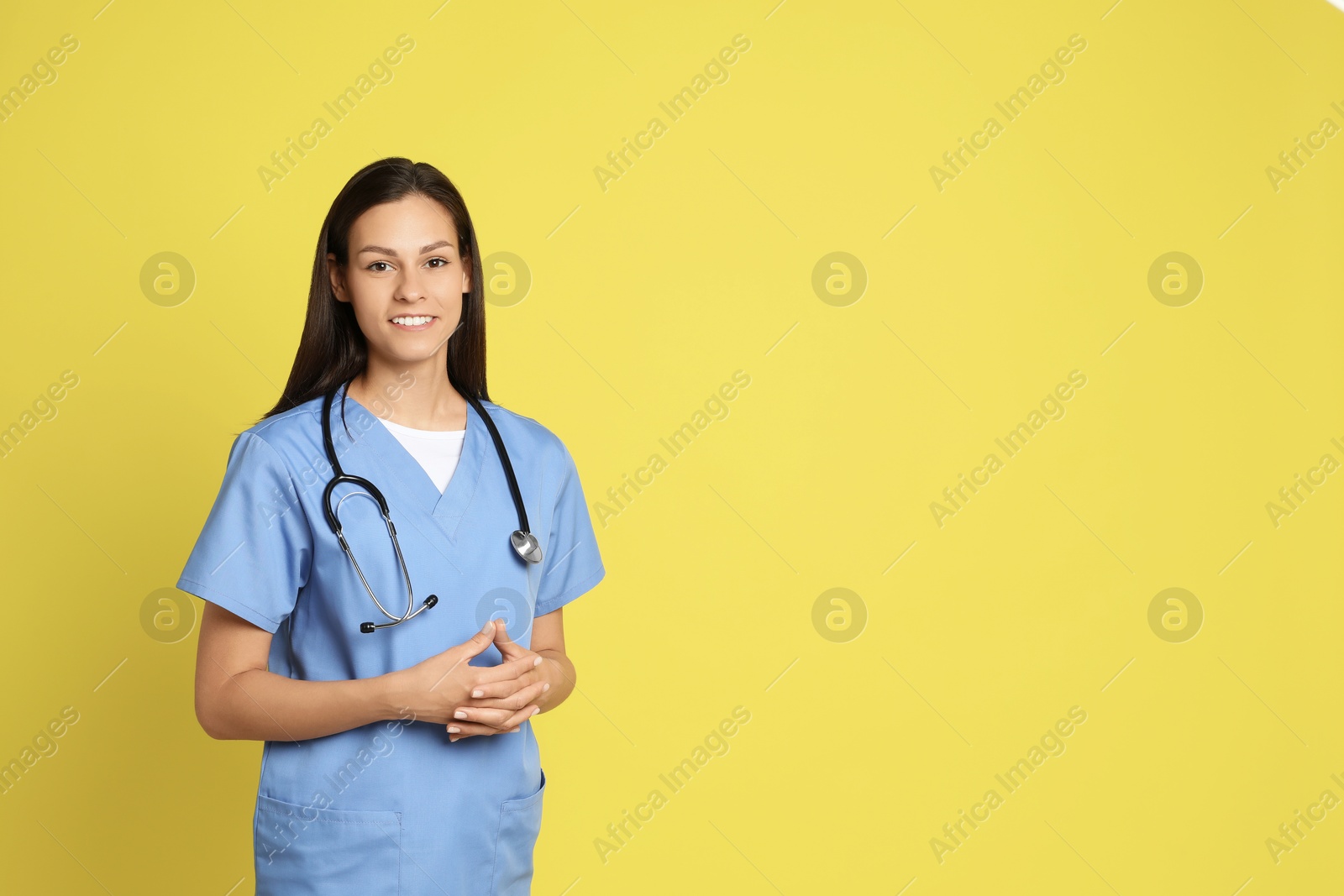 Photo of Portrait of smiling nurse with stethoscope on yellow background. Space for text