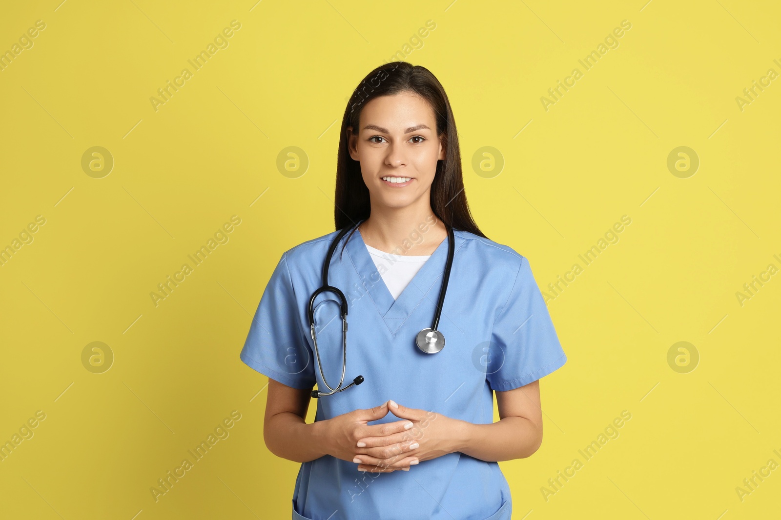 Photo of Portrait of smiling nurse with stethoscope on yellow background