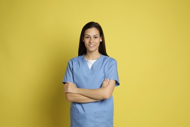 Portrait of smiling nurse with crossed arms on yellow background