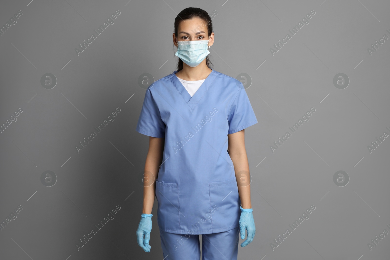 Photo of Portrait of nurse in medical mask and gloves on grey background