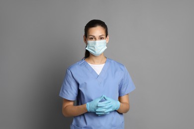 Photo of Portrait of nurse in medical mask and gloves on grey background