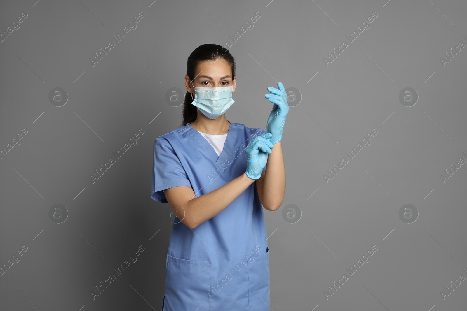 Photo of Portrait of nurse in medical mask and gloves on grey background