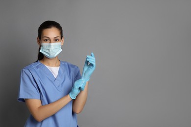 Portrait of nurse in medical mask and gloves on grey background. Space for text