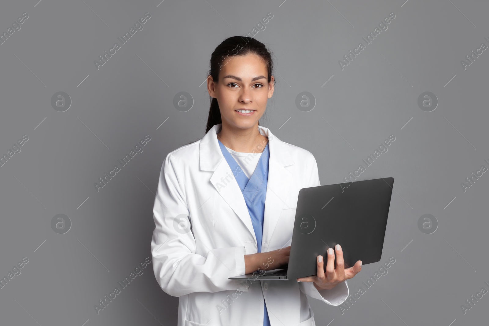 Photo of Portrait of smiling nurse with laptop on grey background