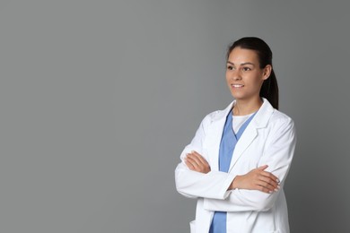 Photo of Portrait of smiling nurse with crossed arms on grey background. Space for text