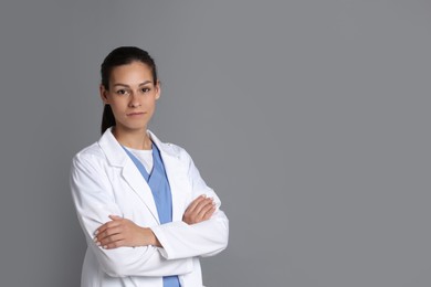 Portrait of beautiful nurse with crossed arms on grey background. Space for text