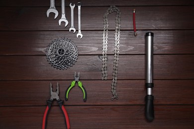 Flat lay composition with different bicycle components and tools on wooden background