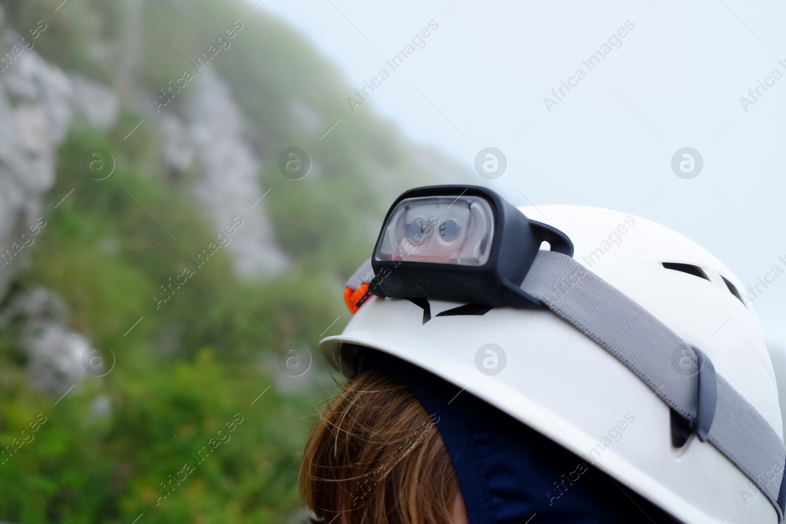 Photo of Kid with helmet and headlamp in mountains, closeup. Space for text