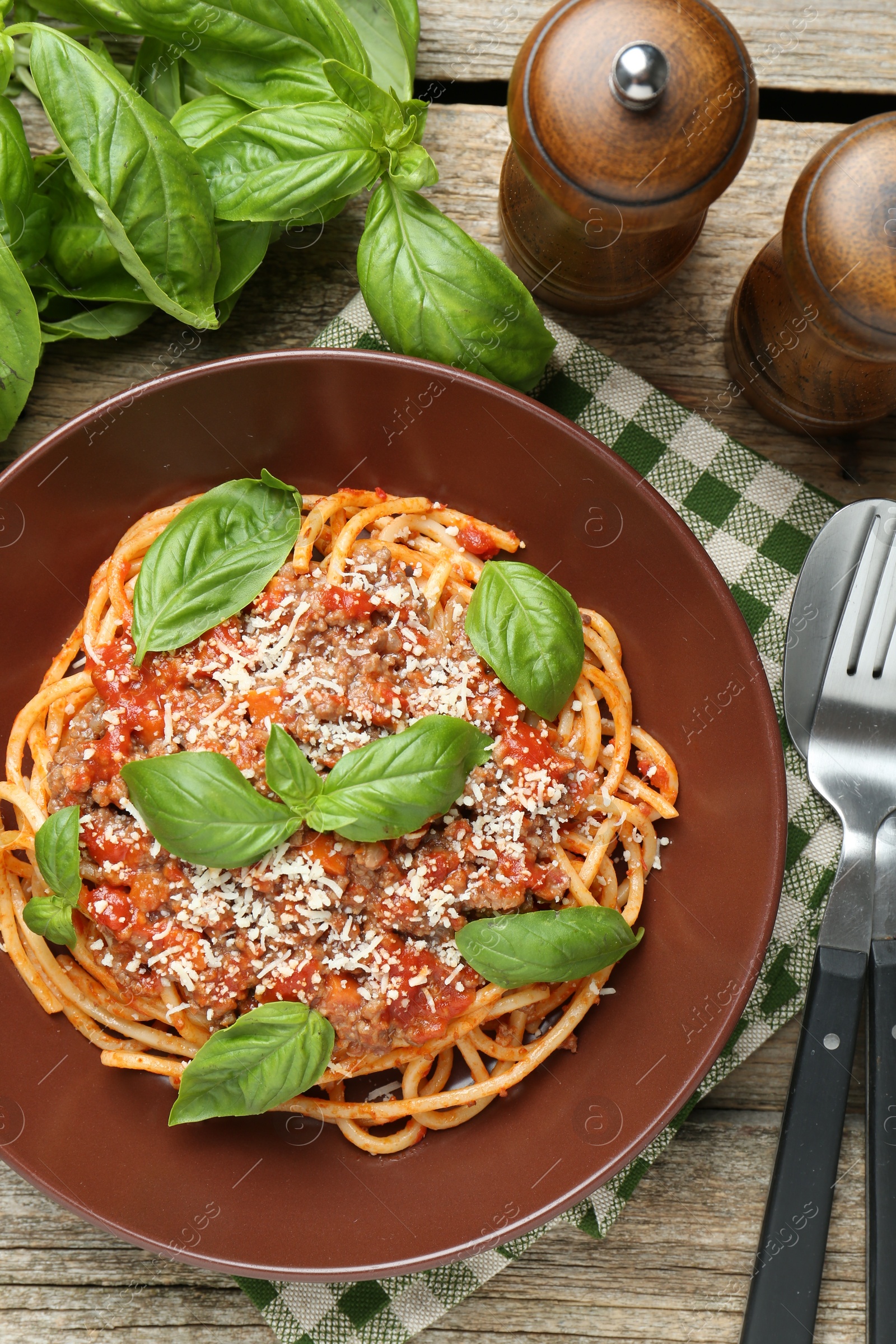 Photo of Delicious pasta bolognese with basil served on wooden table, top view