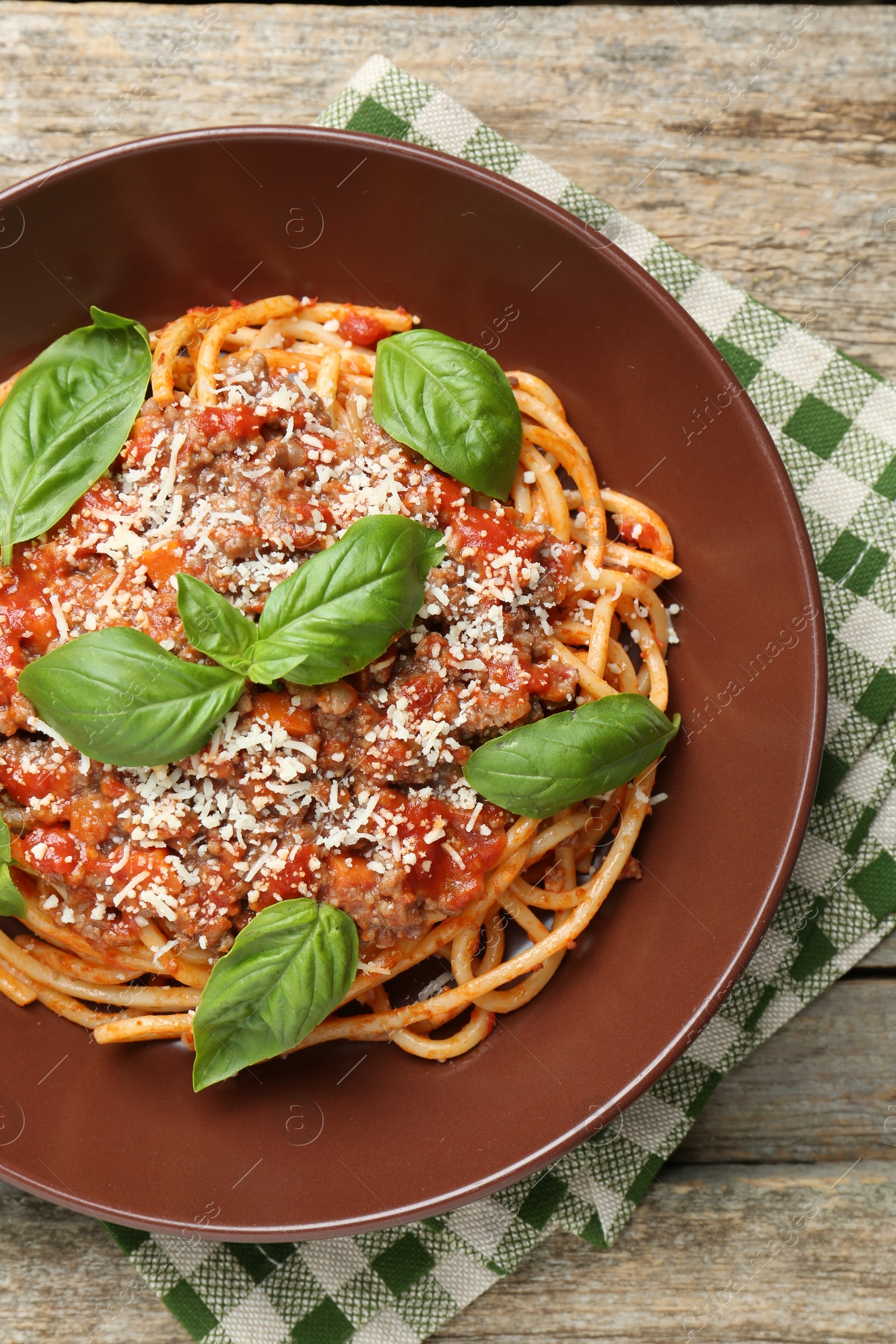 Photo of Delicious pasta bolognese with basil on wooden table, top view