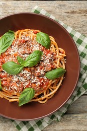 Photo of Delicious pasta bolognese with basil on wooden table, top view