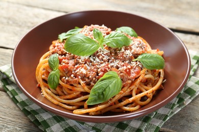 Photo of Delicious pasta bolognese with basil on wooden table, closeup