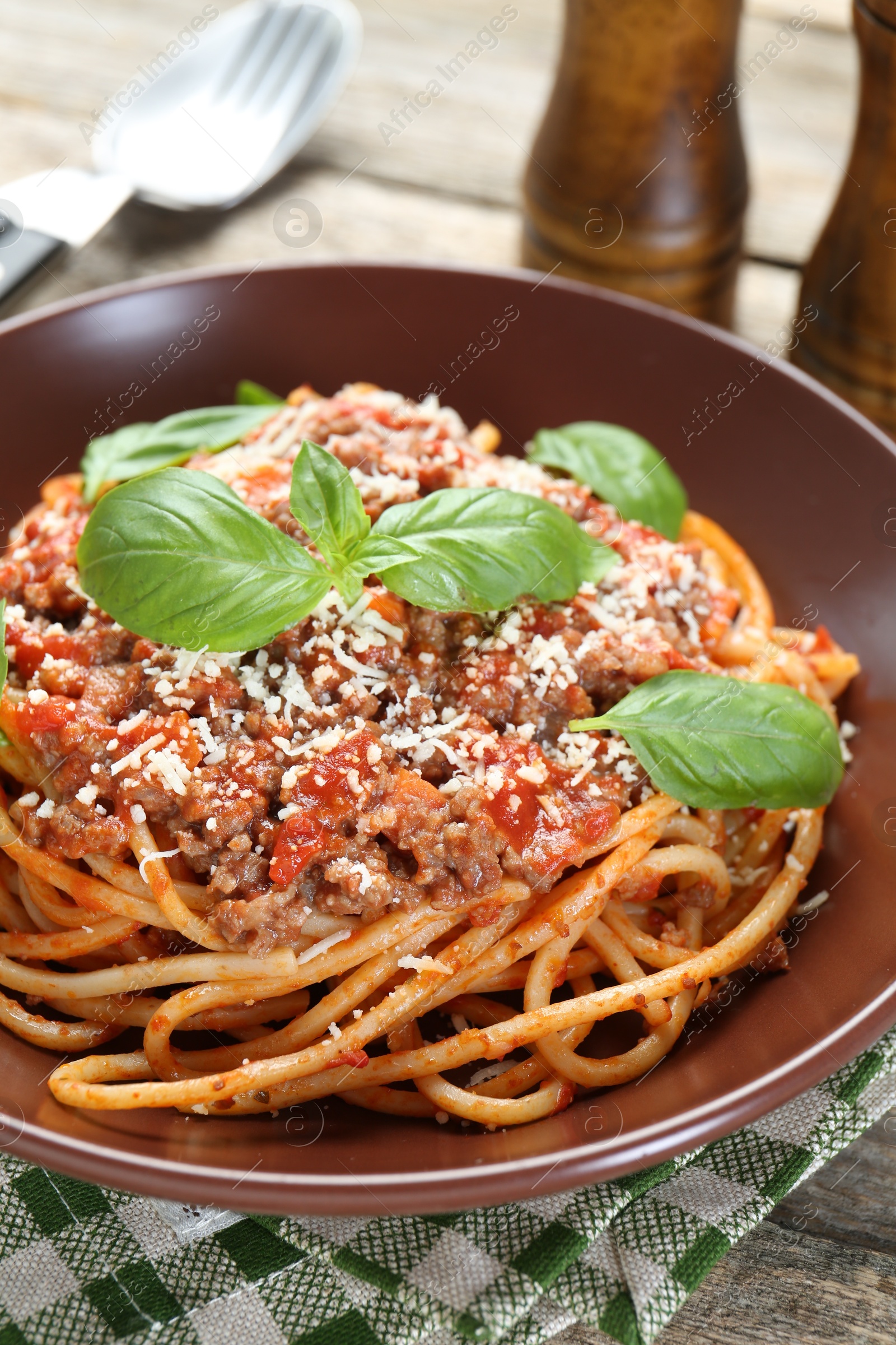 Photo of Delicious pasta bolognese with basil on wooden table, closeup