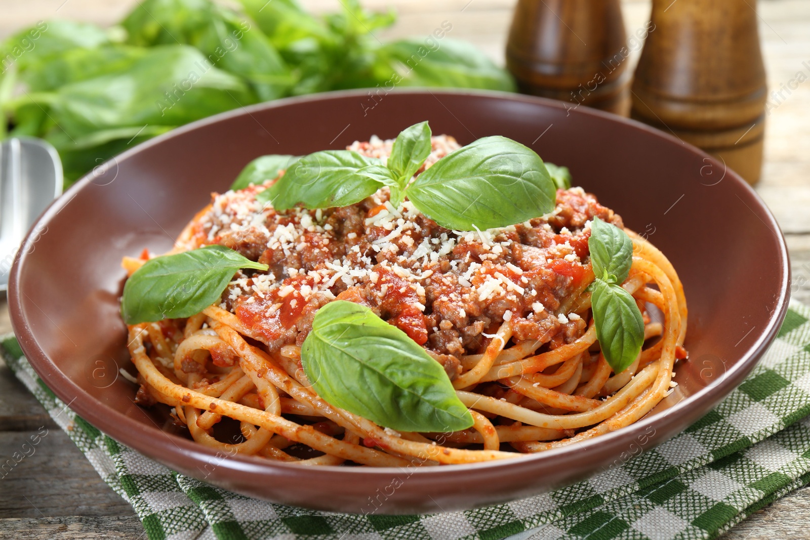 Photo of Delicious pasta bolognese with basil on wooden table, closeup