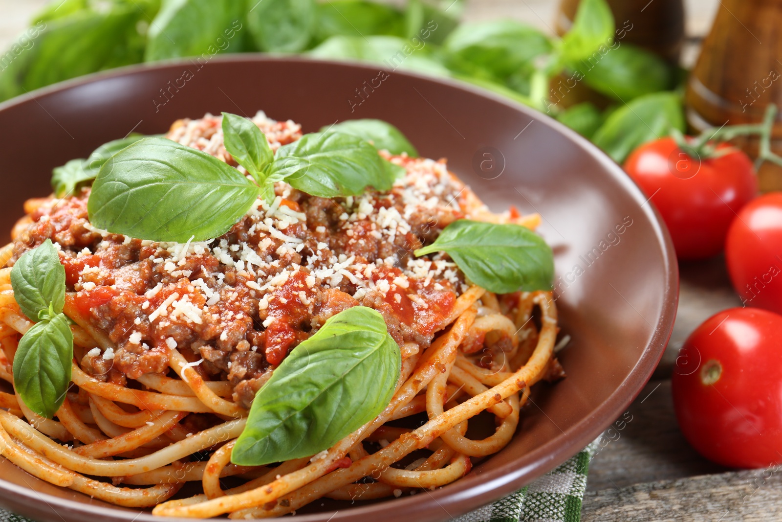 Photo of Delicious pasta bolognese with basil on wooden table, closeup