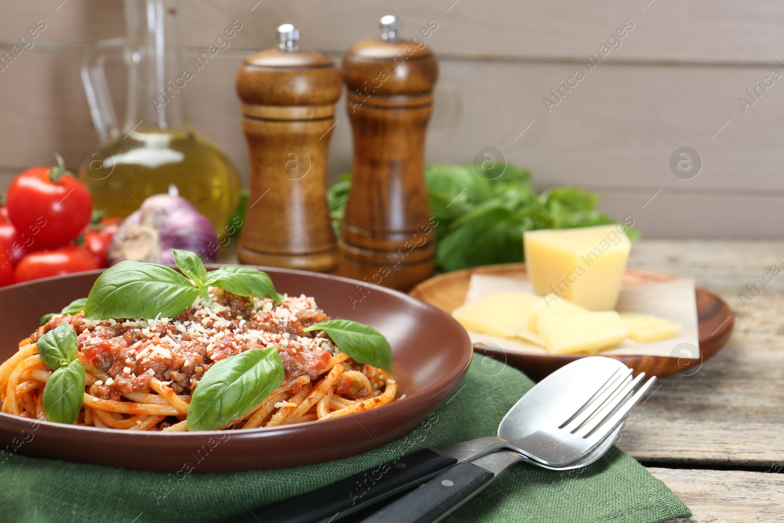 Photo of Delicious pasta bolognese with basil served on wooden table, closeup