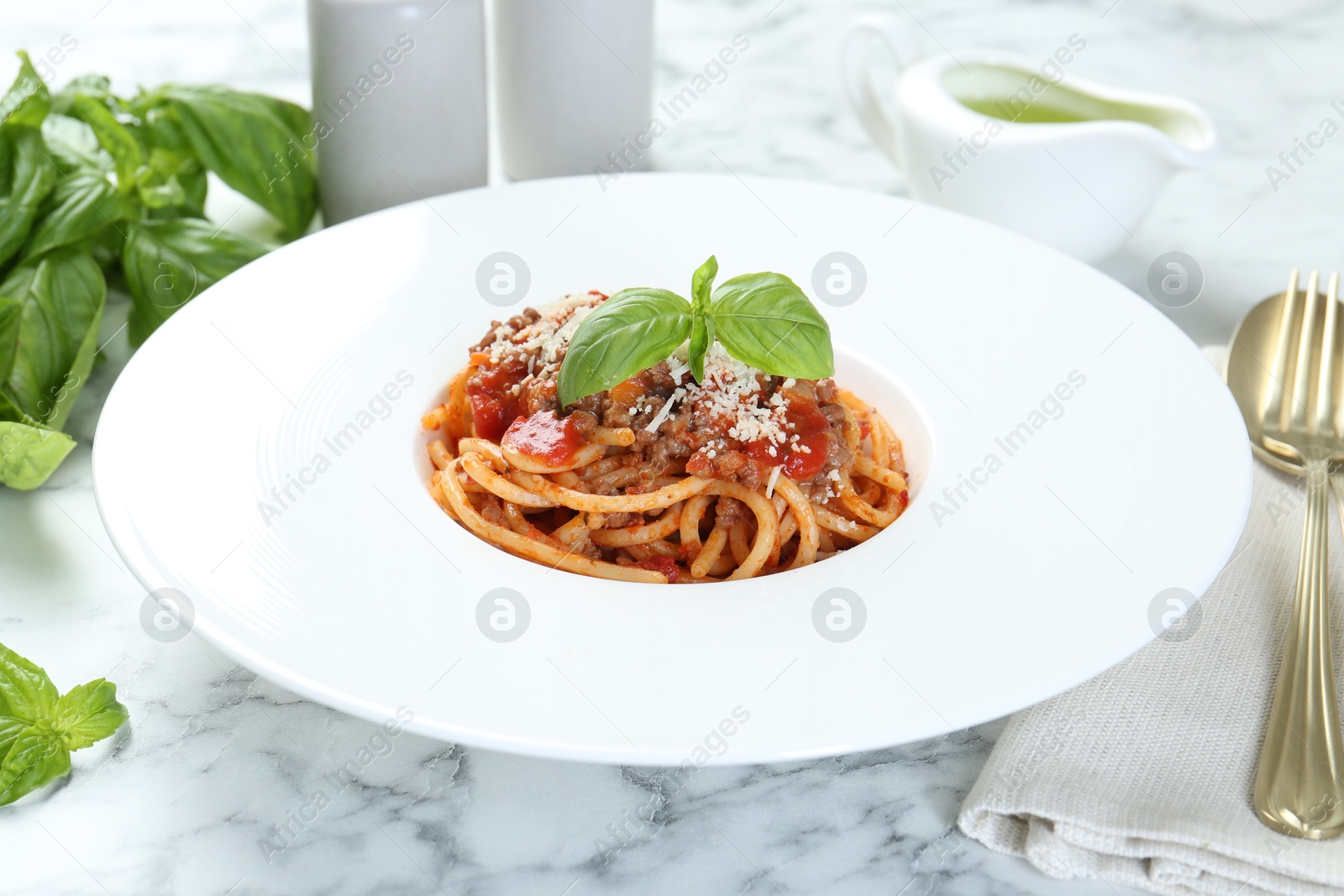 Photo of Delicious pasta bolognese with basil on white marble table, closeup