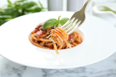 Eating delicious pasta bolognese at white marble table, closeup