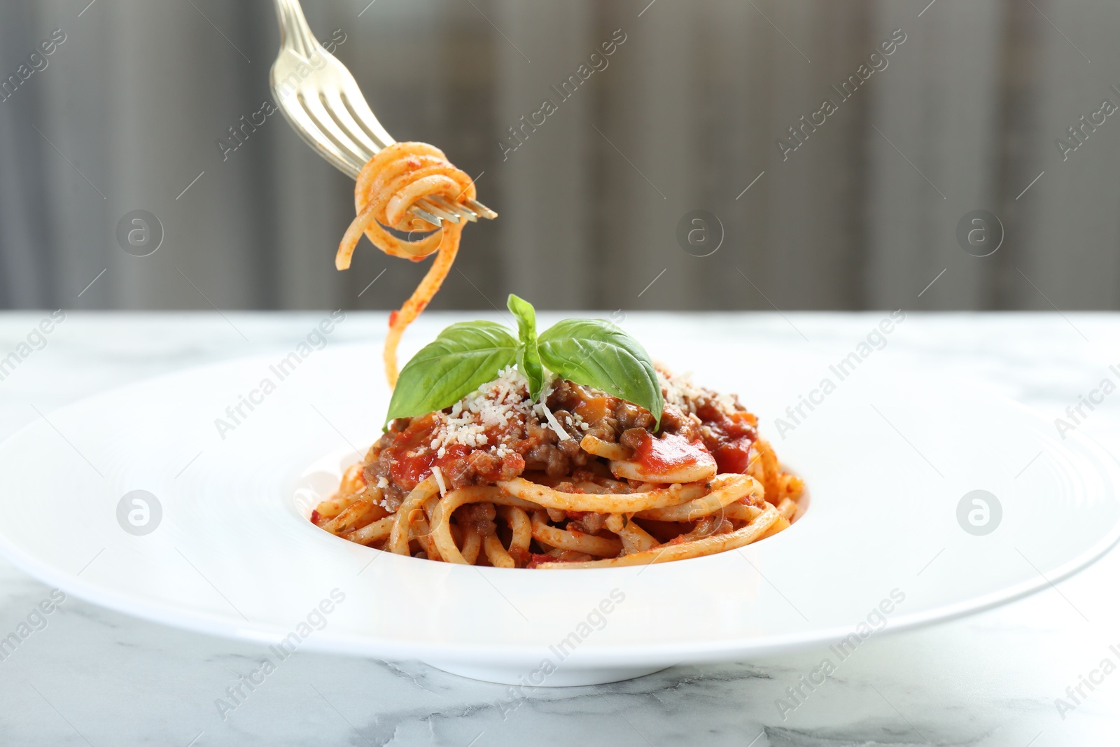 Photo of Eating delicious pasta bolognese at white marble table, closeup