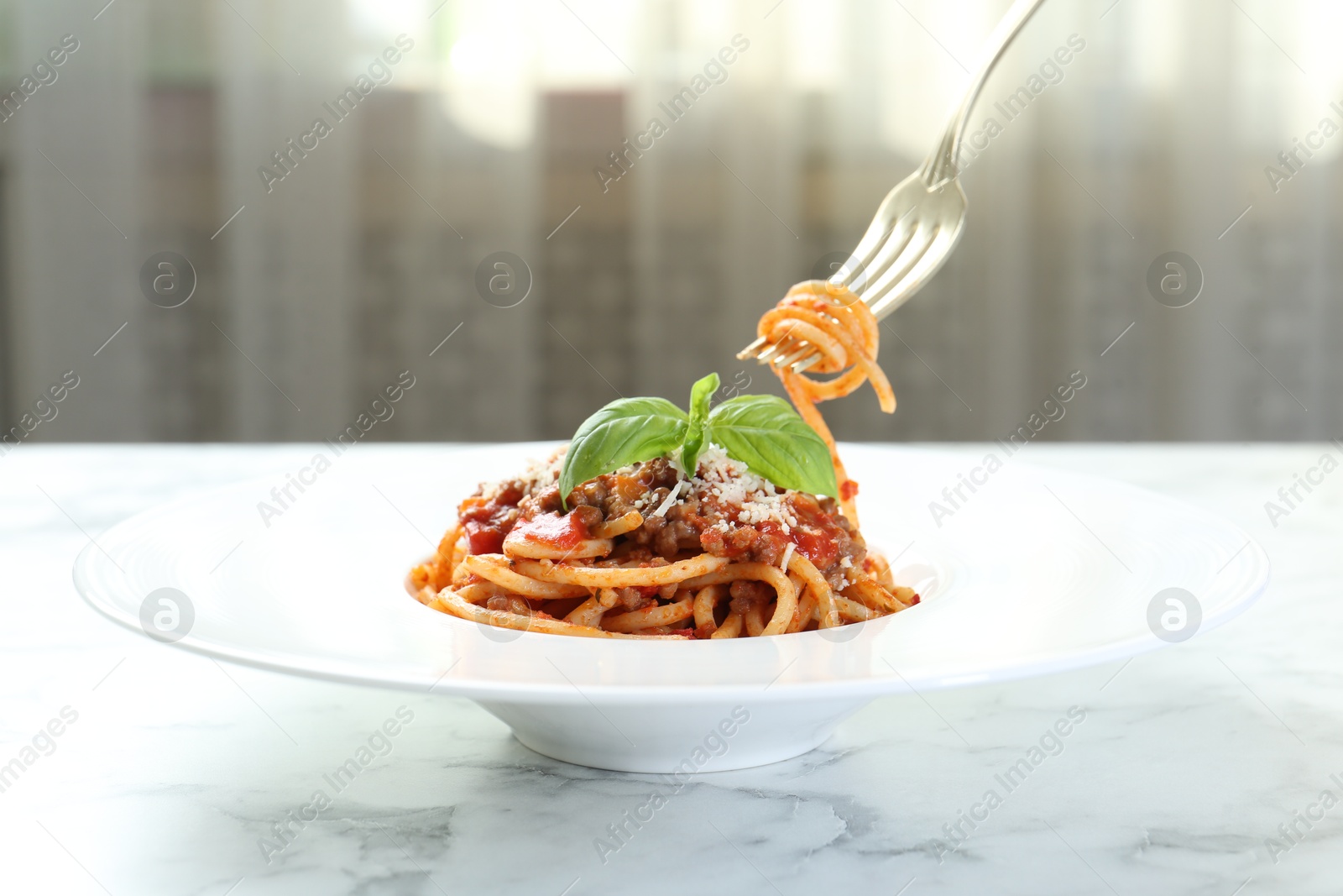 Photo of Eating delicious pasta bolognese at white marble table, closeup