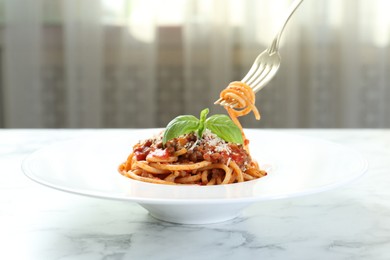 Photo of Eating delicious pasta bolognese at white marble table, closeup