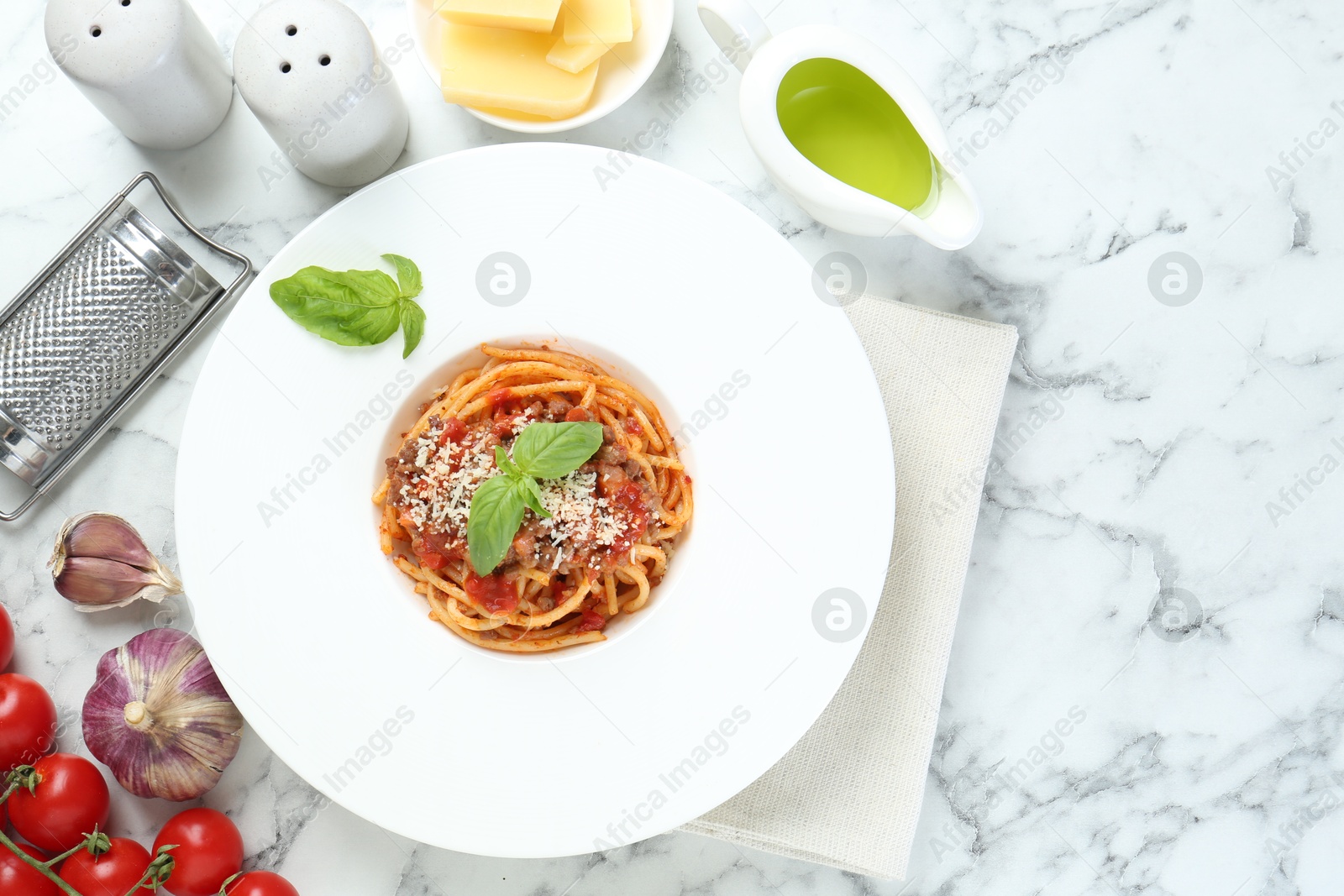 Photo of Delicious pasta bolognese with basil served on white marble table, top view