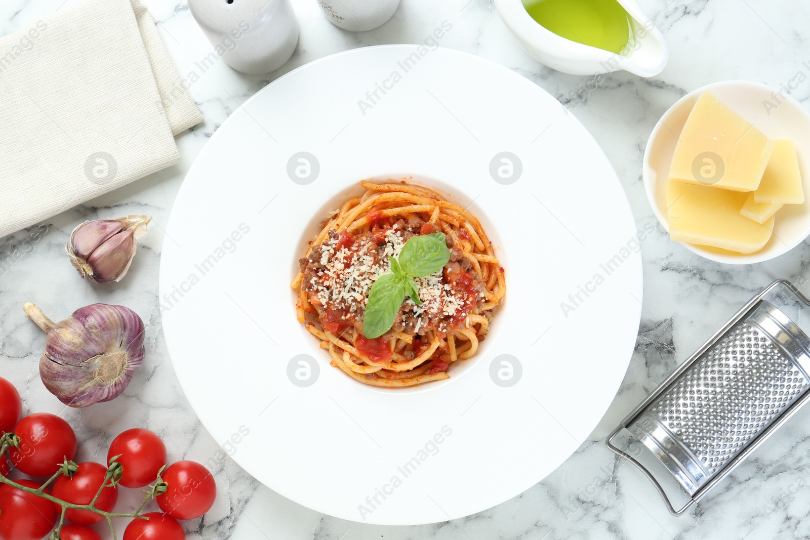 Photo of Delicious pasta bolognese with basil served on white marble table, top view