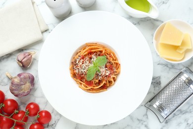 Photo of Delicious pasta bolognese with basil served on white marble table, top view