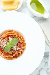 Photo of Delicious pasta bolognese with basil served on white marble table, top view