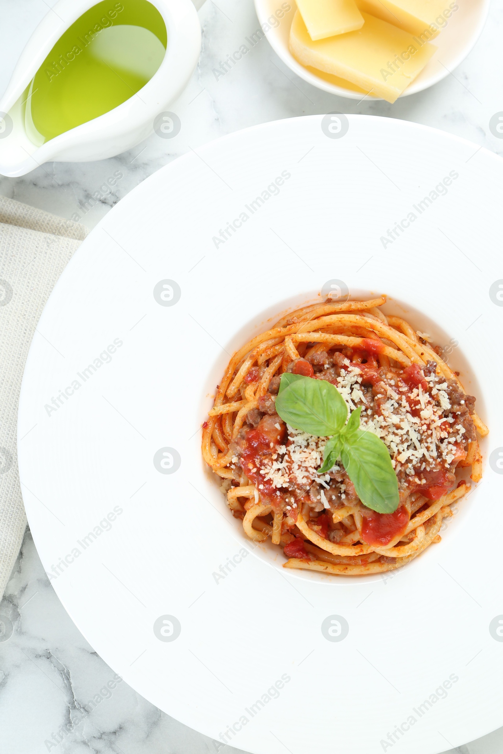 Photo of Delicious pasta bolognese with basil served on white marble table, top view