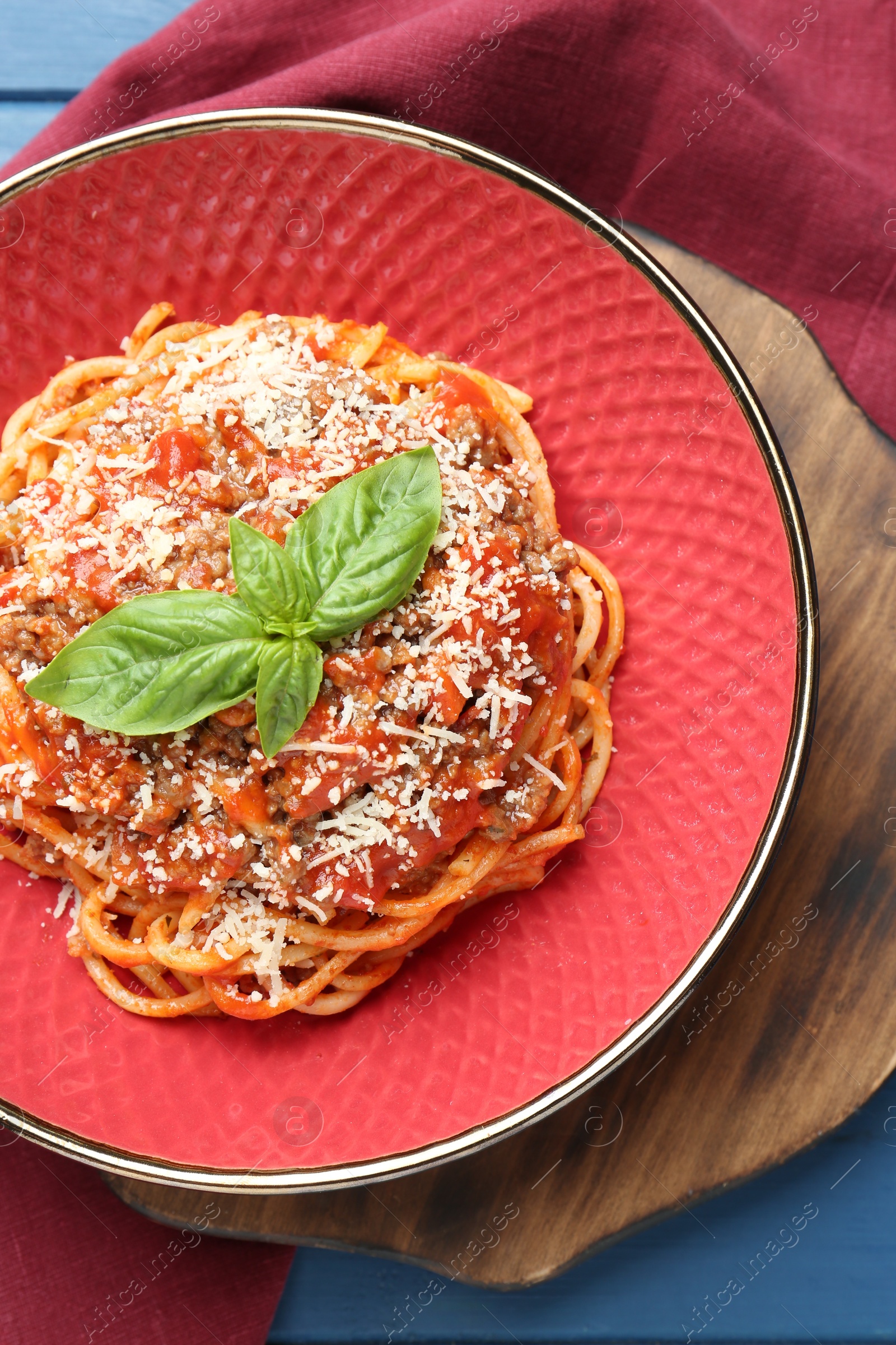 Photo of Delicious pasta bolognese with basil on blue table, top view